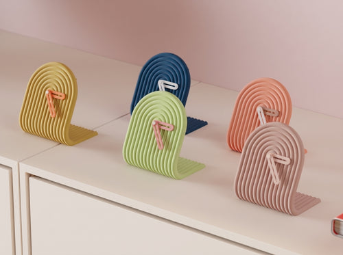 Set of colorful 3D printed clocks on a light colored shelf